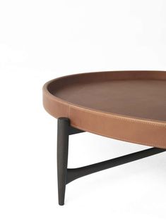 a brown leather tray with black legs on a white background, the tray is shaped to look like a coffee table