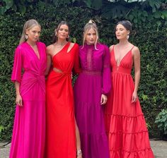 three women in long dresses standing next to each other with one woman wearing a red dress