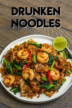 a white plate topped with shrimp and veggies on top of a wooden table