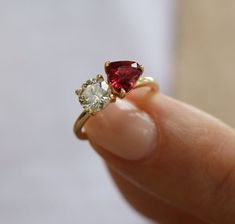 a woman's hand is holding an engagement ring with two stone garnets