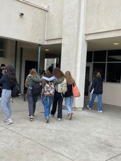 several people are walking in front of a building and one is holding onto another person's hand