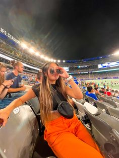 a woman sitting in the stands at a baseball game with her hand on her head