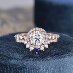 a diamond ring with blue sapphires on top sits on a velvet cushion in front of a box