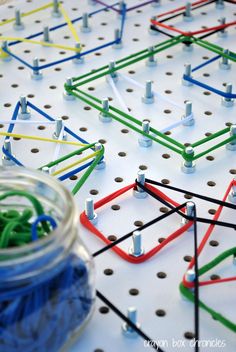 an array of colored pegs and pins on a white board with a glass jar