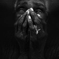 a black and white photo of an african woman with her hands on her face, covering her eyes