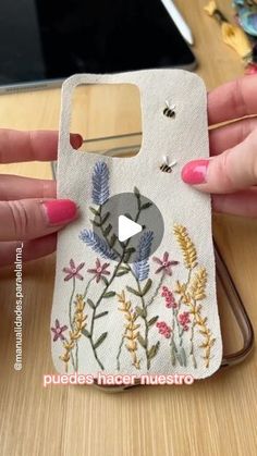 a woman holding up a phone case with flowers on it