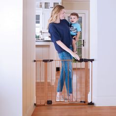 a woman holding a baby in her arms while standing on a stair gate that is open