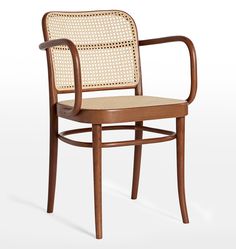 a wooden chair with wicker back and arm rests on a white surface, in front of an off - white background