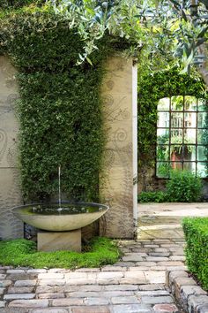 an outdoor bathtub surrounded by greenery in the middle of a stone patio area