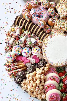 a platter filled with lots of different types of donuts and other treats on top of it