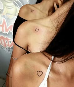 two women with tattoos on their backs and one has a small heart tattoo on her left shoulder