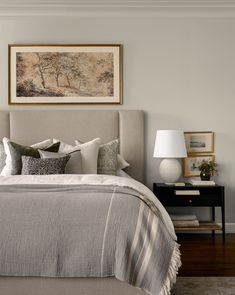 a bedroom with a bed, nightstand and painting on the wall