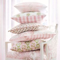 a stack of pillows sitting on top of a white chair