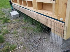 a chicken coop built into the side of a building with wooden shelves and wire fencing around it