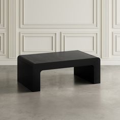 a black coffee table sitting in front of a wall with white paneling on it