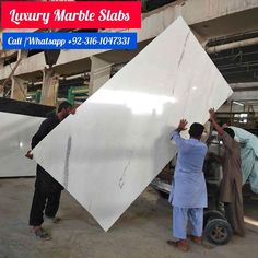 two men working on a large white slab in a factory with another man standing next to it