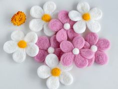 small white and pink felt flowers next to an orange flower