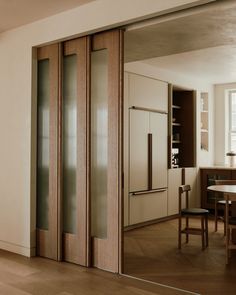 an open sliding door in the middle of a dining room with wooden floors and white walls