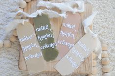 three bookmarks with words on them sitting on a wooden board surrounded by white beads