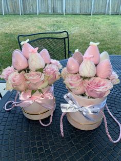 two vases filled with pink flowers sitting on top of a black tablecloth covered patio