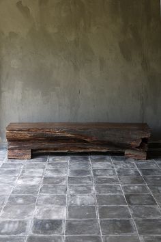 a wooden bench sitting on top of a tiled floor next to a wall and window