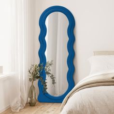 a bedroom with a large blue mirror on the wall next to a bed and window