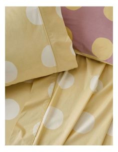 a bed with yellow and white polka dot sheets