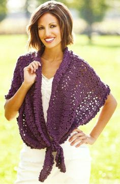 a woman wearing a purple crocheted shawl in the grass with her hands on her hips