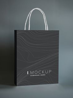 a black shopping bag with the word mockup printed on it, against a grey background