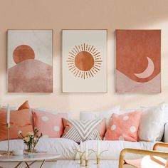 three paintings hang on the wall above a couch with pillows and coffee table in front of it