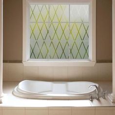 a bathtub sitting under a window in a bathroom next to columns and a tiled floor