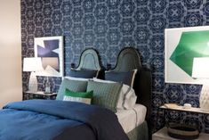 a bedroom with blue and green wallpaper, white bedding and two nightstands