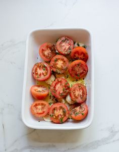 sliced tomatoes in a white dish on a marble counter