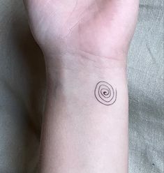 a person's wrist with a small black and white spiral tattoo on the wrist