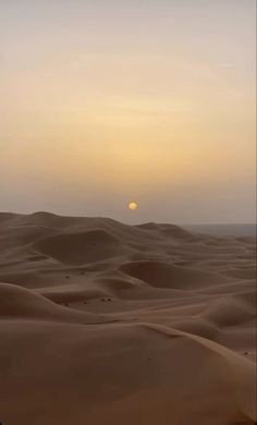 the sun is setting over sand dunes in the desert