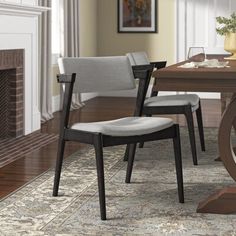 a dining room table with two chairs and a rug on the floor in front of it