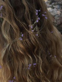 the back of a woman's head with purple flowers in her hair