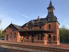 an old red brick train station with a clock on it's tower and steeple