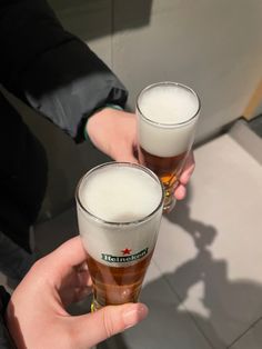 two people holding up glasses of beer in their hands