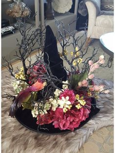 a black hat with flowers and branches in it sitting on a furnishing area