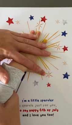 someone cutting out a fourth of july greeting card with scissors and glue on the paper