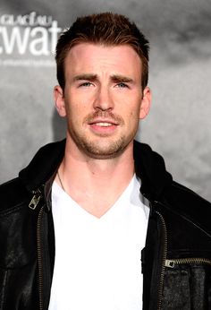 a close up of a person wearing a black jacket and white t - shirt in front of a gray background