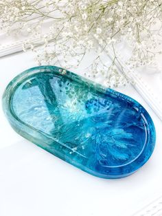 a blue tray sitting on top of a white table next to a vase with flowers