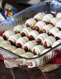 a casserole dish filled with hotdogs wrapped in white icing and sitting on a table