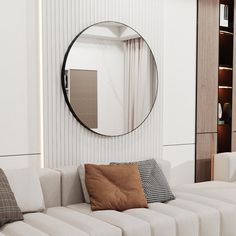 a living room with white couches and a round mirror on the wall