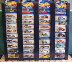 three display cases filled with hot wheels cars on top of a carpeted floor in front of a blue couch