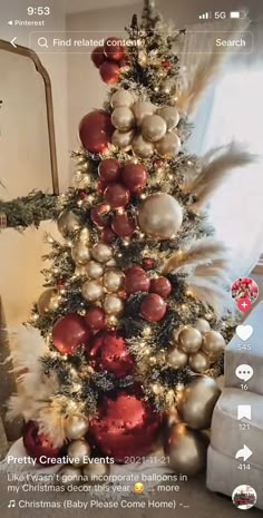 the christmas tree is decorated with red and gold baubs, feathers, and ornaments