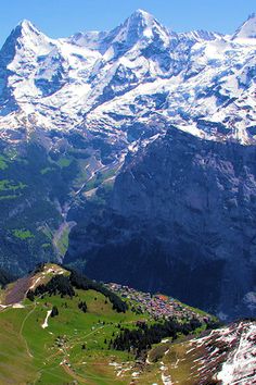 the mountains are covered in snow and green grass