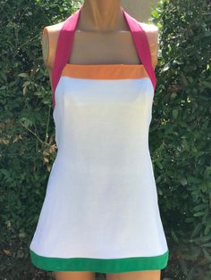 Here is a vintage 1970s white halter polyester tennis dress.Following are the measurements, Bust 32",waist 30",Hips 38",Length 29".Zips up the back.White color with pink, green , orange trim.Nice vintage condition.If you live overseas please email me before purchasing for mailing cost. Price quoted is for USA only. Please take special note of measurements. 1970s sizing was much smaller than today's standards. Tennis dresses were very short not like a regular dress. So please take special note of lengths White A-line Halter Dress For Summer, White Stretch Halter Dress For Summer, Fitted Retro Summer Halter Dress, Fitted Retro Halter Dress For Summer, White Cotton Tennis Dress For Summer, White Cotton Halter Neck Dress, Summer White Cotton Halter Dress, White Fitted Halter Dress, White Fitted Halter Neck Dress