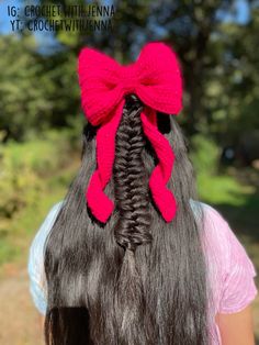 a girl with long dark hair wearing a red knitted bow in her back's hair